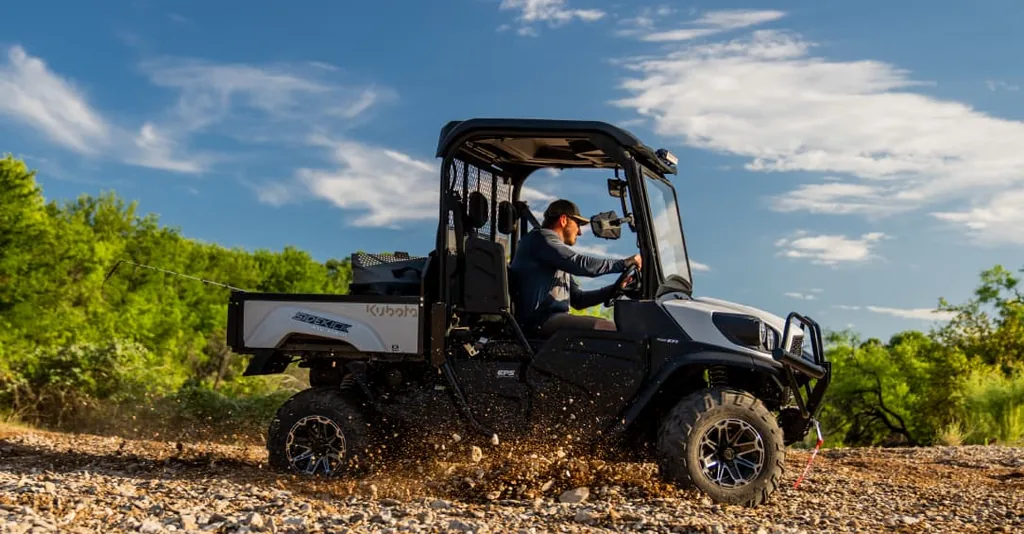 Kubota Sidekick utility vehicle driving on a gravel trail